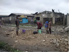 Four men fill in roads with piles of rubble