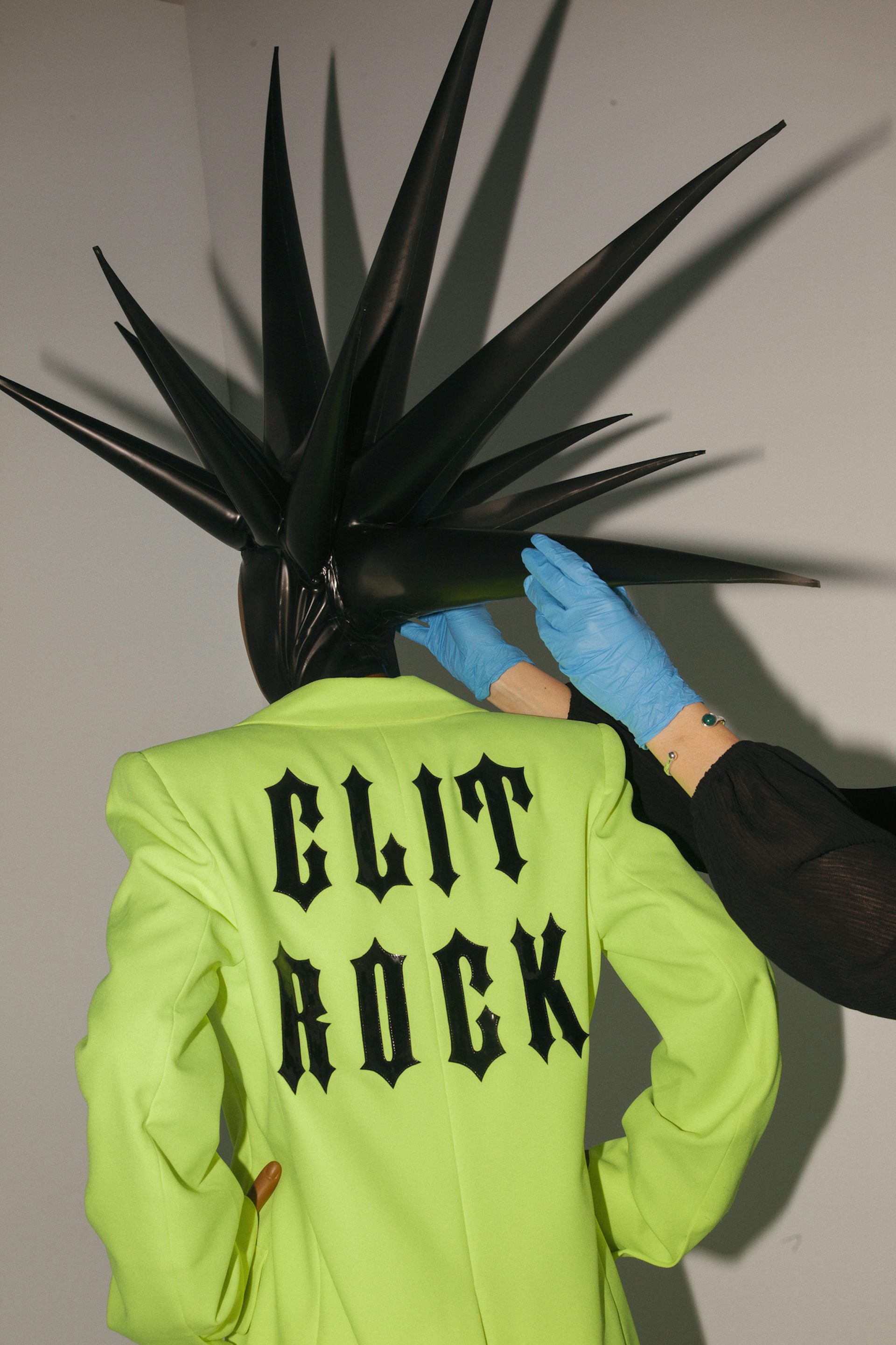 V&A East Museum team prepares Skin's 2022 clit rock ensemble, a bright green jacket with the words stamped on the back.