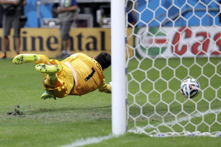 Kiper Prancis, Hugo Lloris, berusaha menyelamatkan gawangnya dengan melompat tetapi tidak mampu menghentikan gol dari tendangan bebas Blerim Dzemaili dari Swiss selama pertandingan sepak bola Piala Dunia antara Swiss dan Prancis pada tahun 2014.