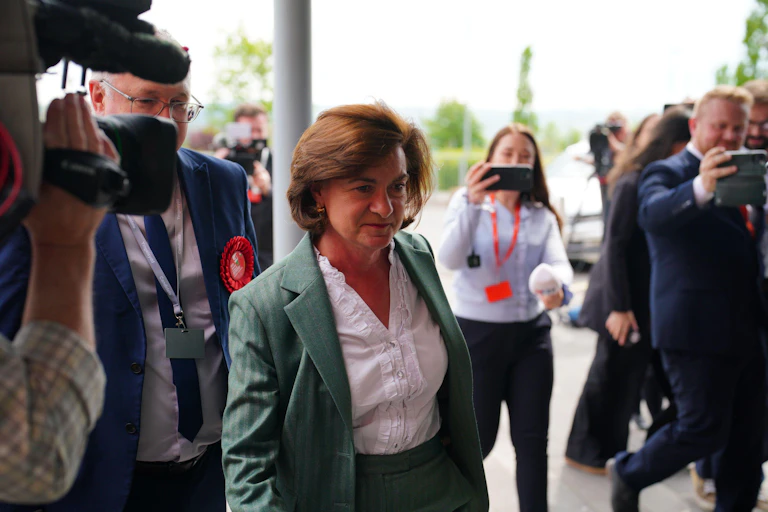 Eluned Morgan walks past a group of cameramen.