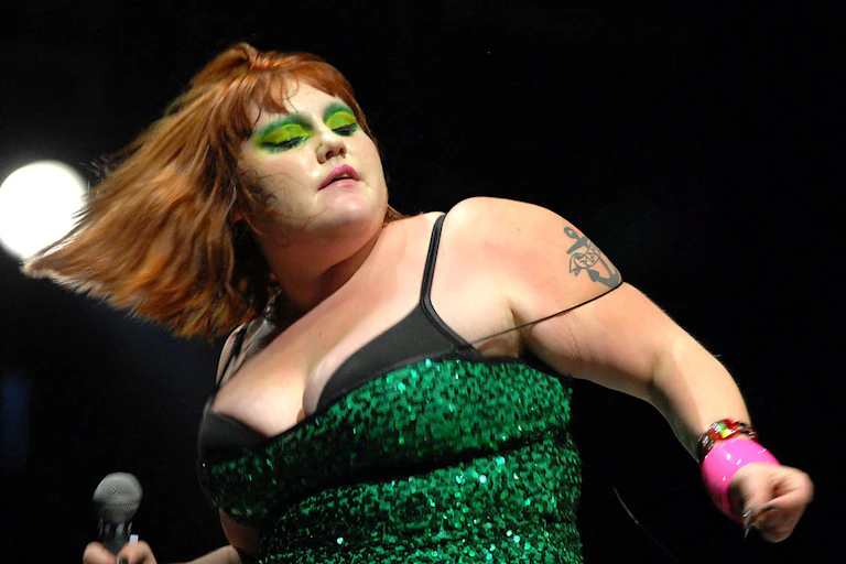 Beth Ditto on stage in a sparkly green dress and matching eyeshadow.