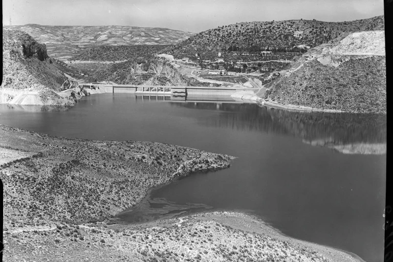 Fotografía de una presa al fondo de un embalse, entre montañas