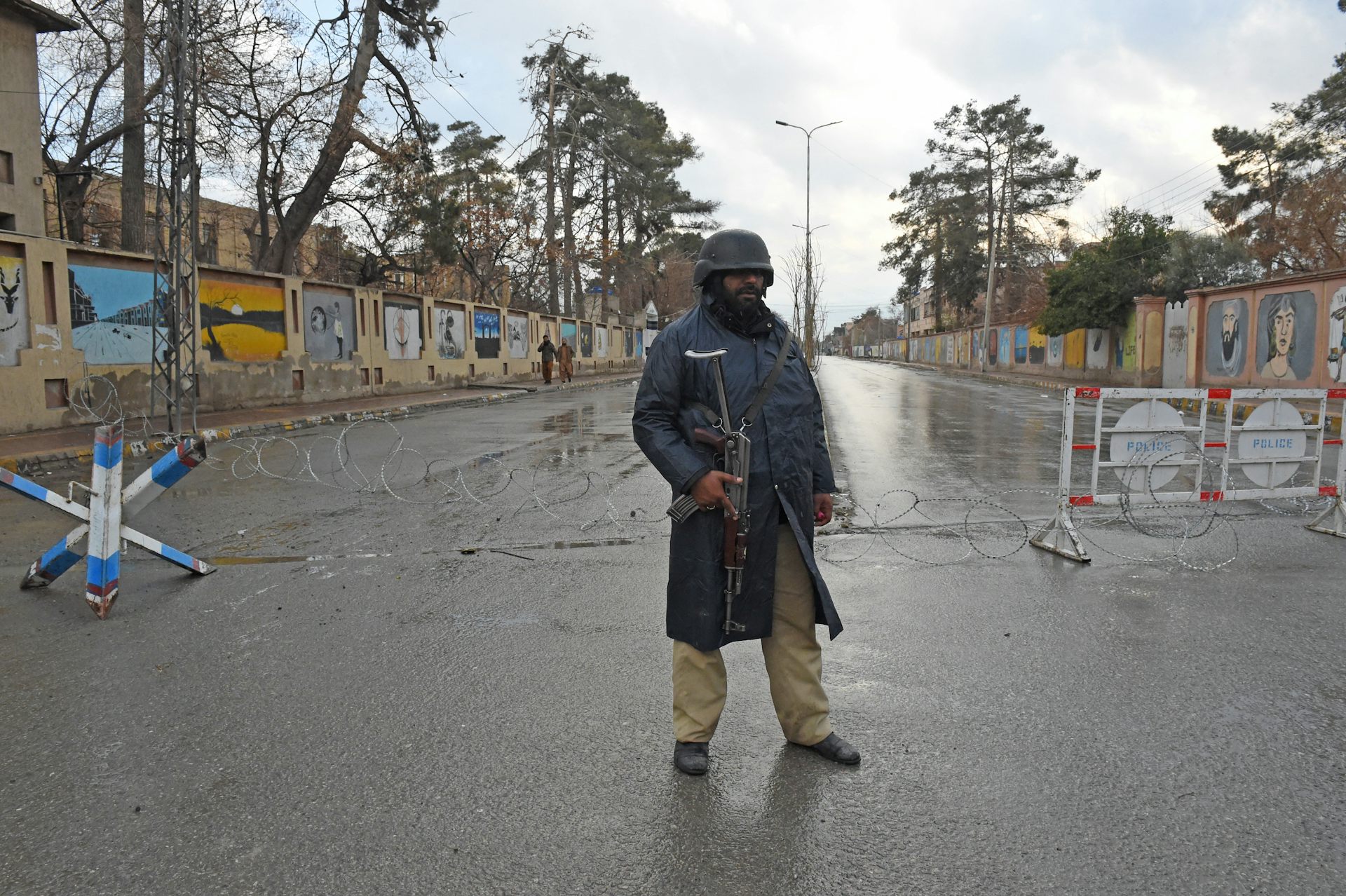 A man in a gun stands in the middle of a street.