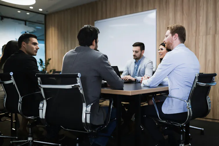 A group of people, nearly all men, sitting at a conference table
