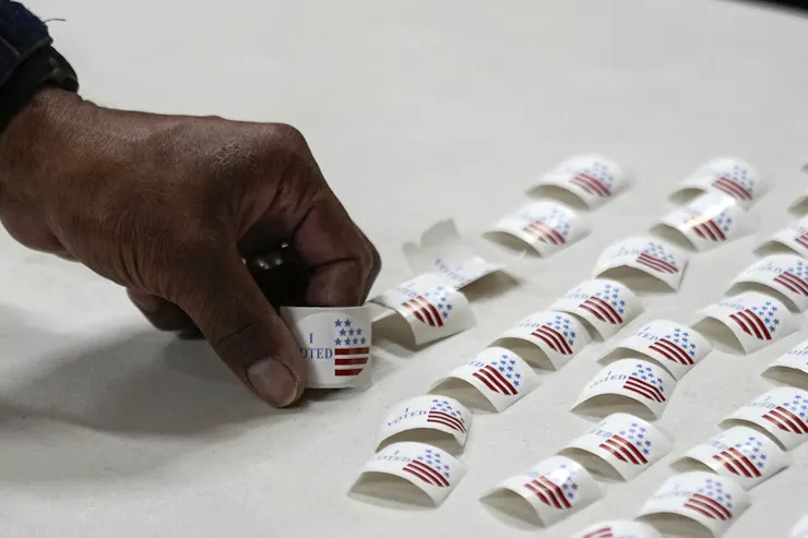 A hand picks up a sticker off a table.