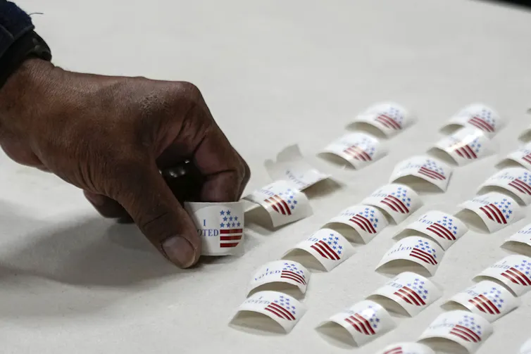 A hand picks up a sticker off a table.