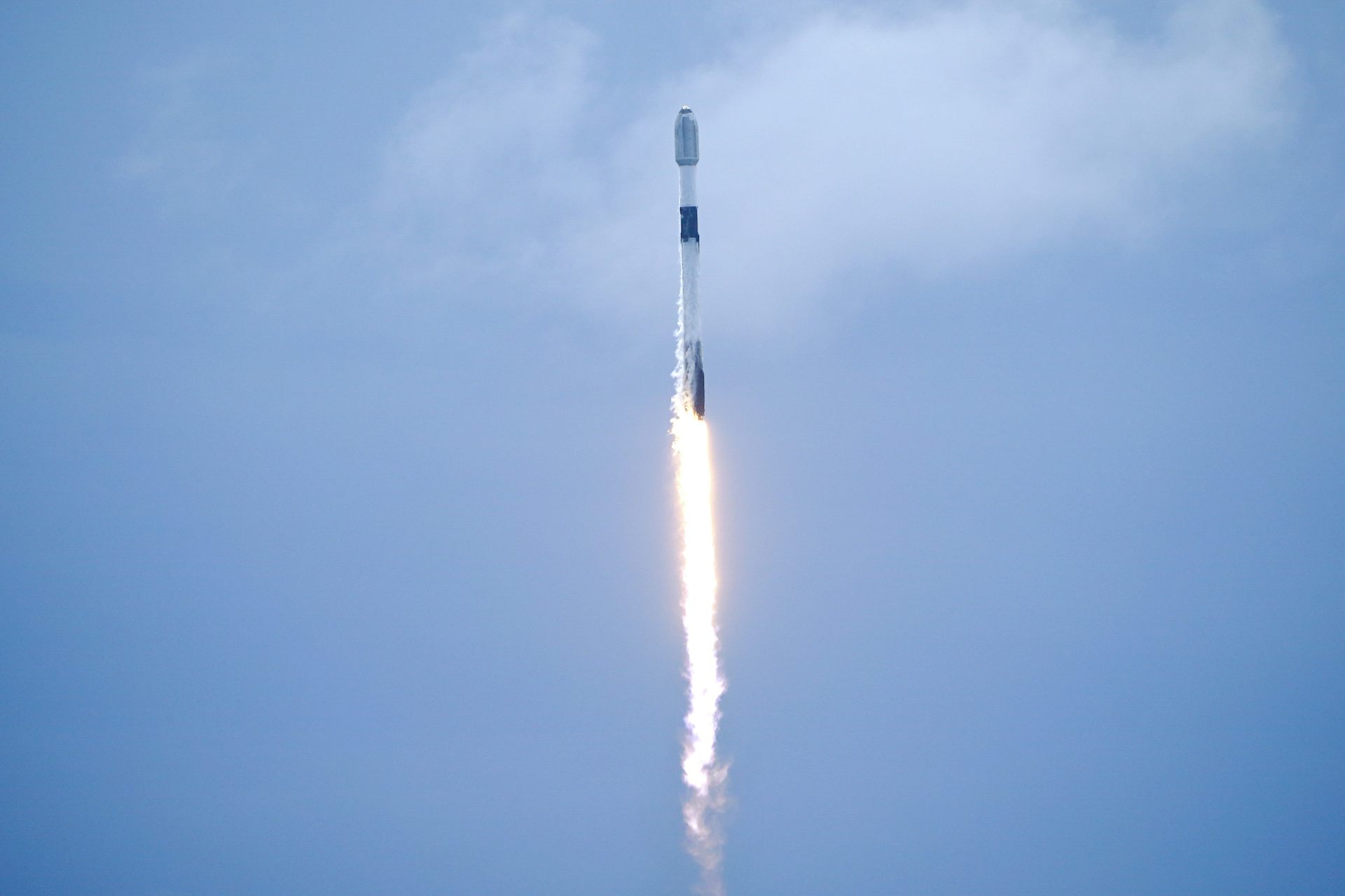 A satellite launches against a blue sky.