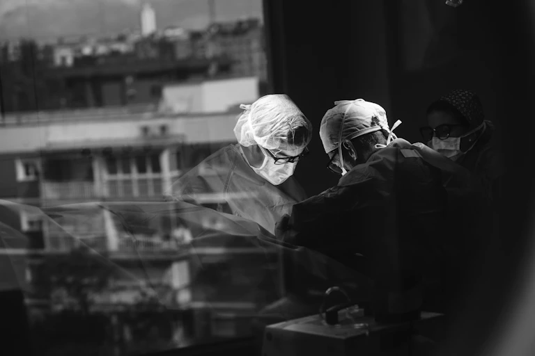 Black and white image of surgeon at work reflected in window