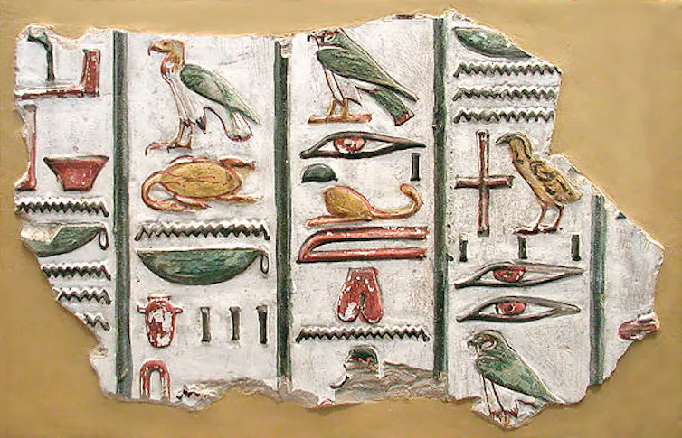 Egyptian hieroglyphs depicting birds, eyes and other images in green, red and gold colour.