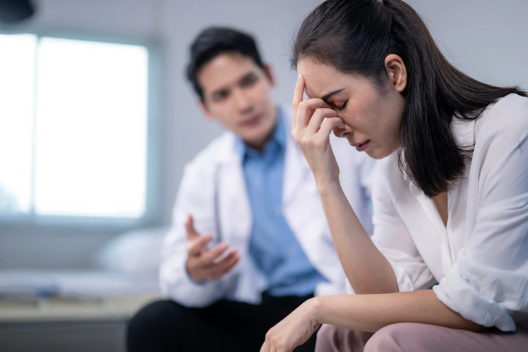 Un médico habla con una paciente con cara de sufrimiento