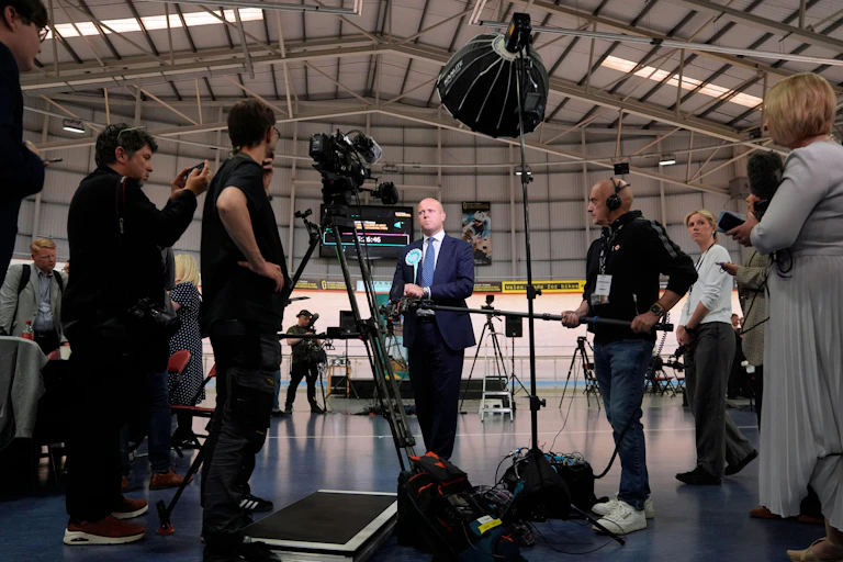 Dan Thomas surrounded by cameras and microphones.