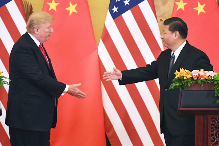 US president, Donald Trump, and Chinese president, Xi Jinping, about to shake hands with tyhe US and CHinese flags in the background.