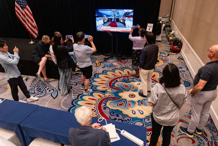 Journalists surround a television set which is showing US president DOnald Trump arriving in Beijing.