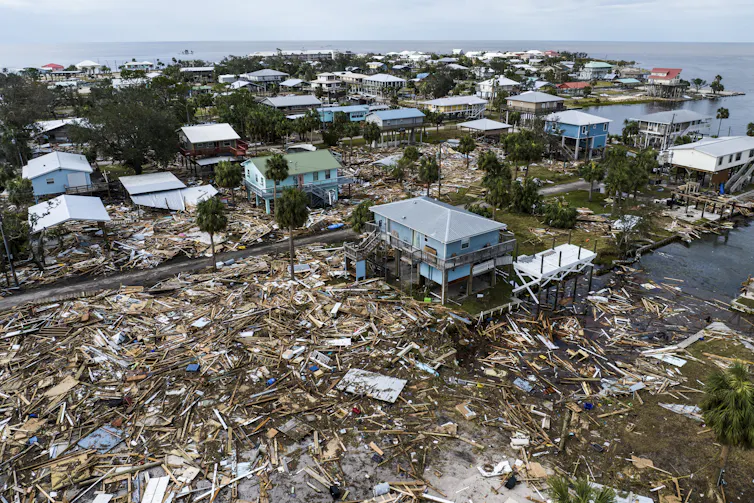 Los pronósticos de huracanes mejoran dramáticamente, salvando vidas, pero los recortes federales amenazan con llevar a la NOAA al límite 4 Escombros y casas dañadas por toda la ciudad con las aguas del Golfo al fondo.
