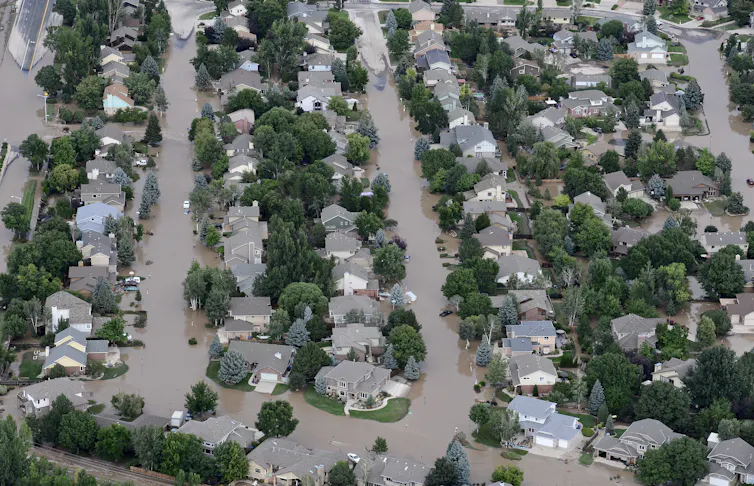 An aerial view of a neighborhood with muddy water filling streets and yards.