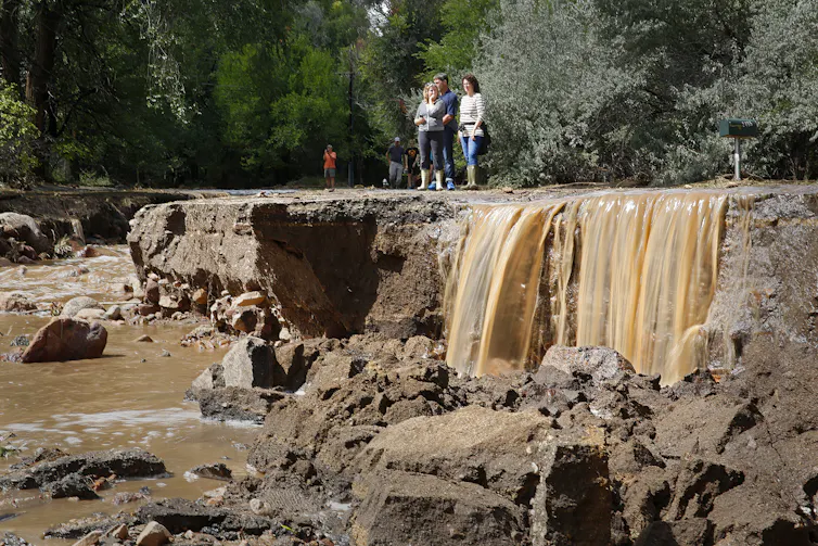 La Constitución y las leyes de Estados Unidos no protegen a las empresas petroleras de ser demandadas por dañar el clima. 2 La gente se encuentra en una carretera erosionada por el agua, que todavía fluye cerca.