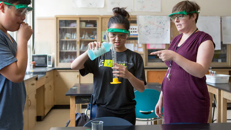 Cómo la enseñanza de la historia de la ciencia puede ayudar a preparar a los estudiantes para afrontar tiempos polarizados 1 Profesor en visera con dos estudiantes sosteniendo equipo de química.