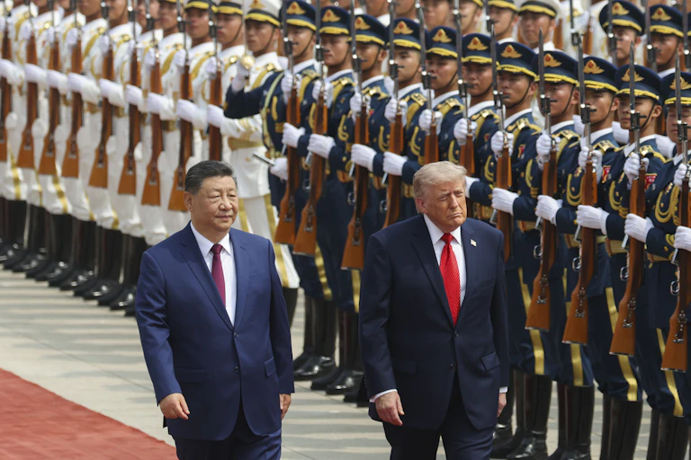 Chinese president, Xi Jinping, and US president, Donald Trump,walk along a red carpet in front of ranks of solduers in ceremonial uniform,.