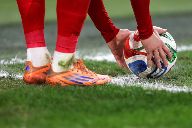 Um homem de meias vermelhas coloca uma bola no gramado.