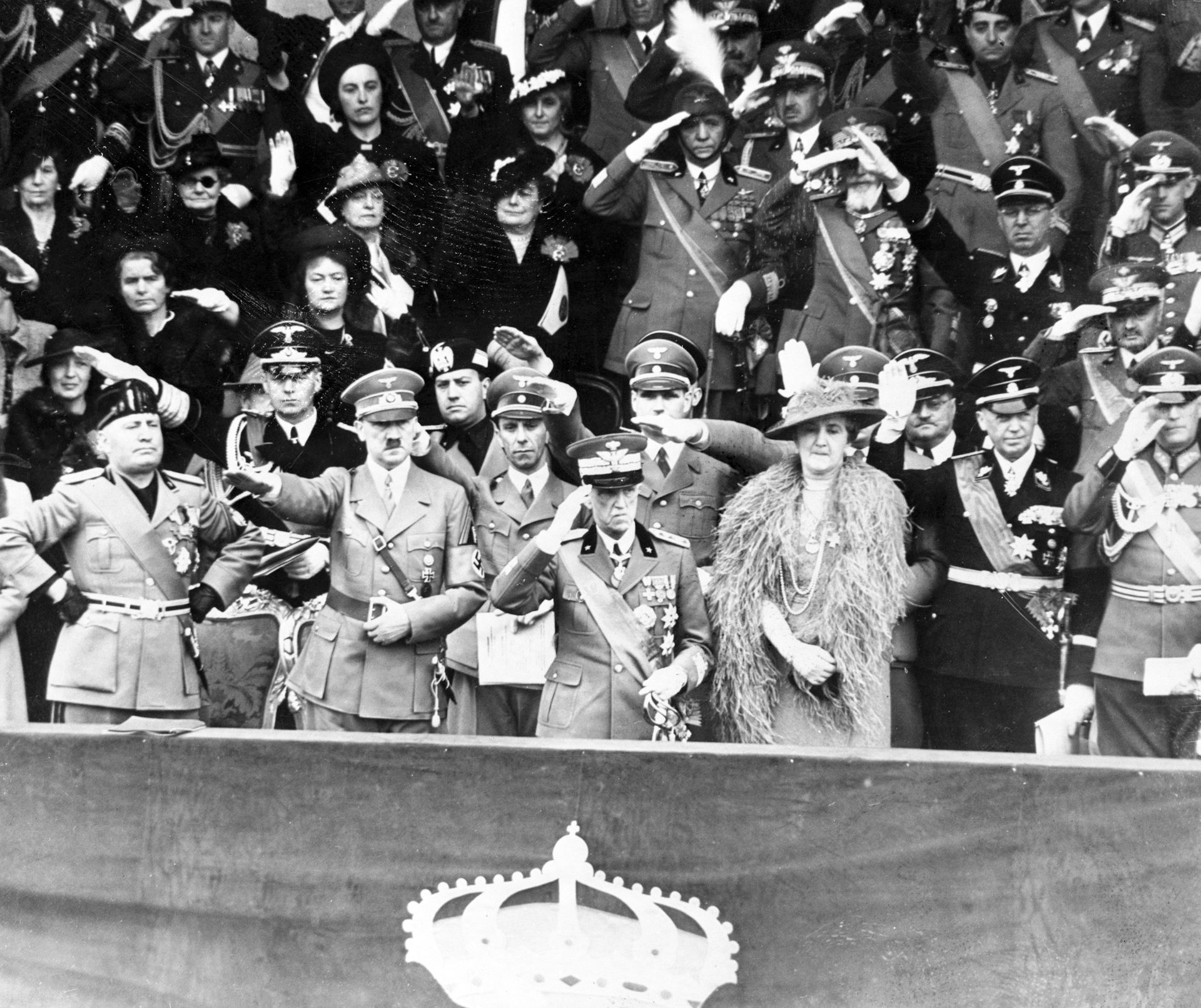 Benito Mussolini stands beside Adolf Hitler as they watch a military parade