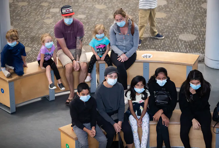 Después de la pandemia de COVID-19, miles de niños más de jardín de infantes enfrentaron desafíos de desarrollo 1 Personas sentadas en bancos con mascarillas escuchando la presentación.