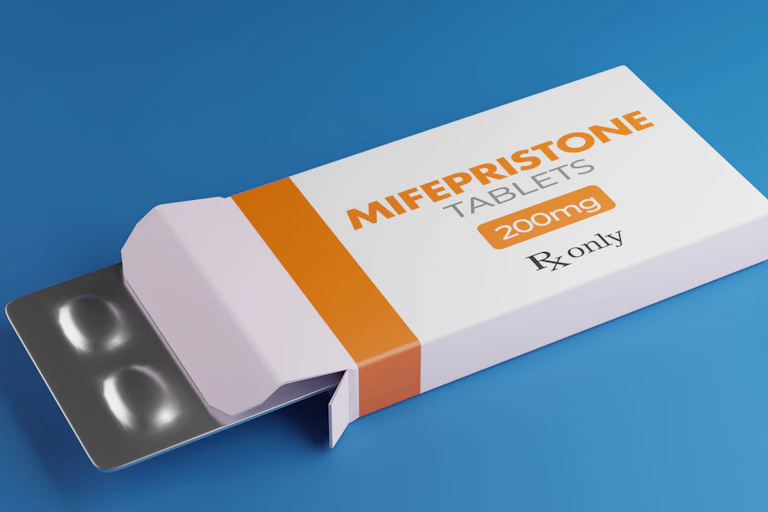 Mifepristone tablets in white box lying on blue background.