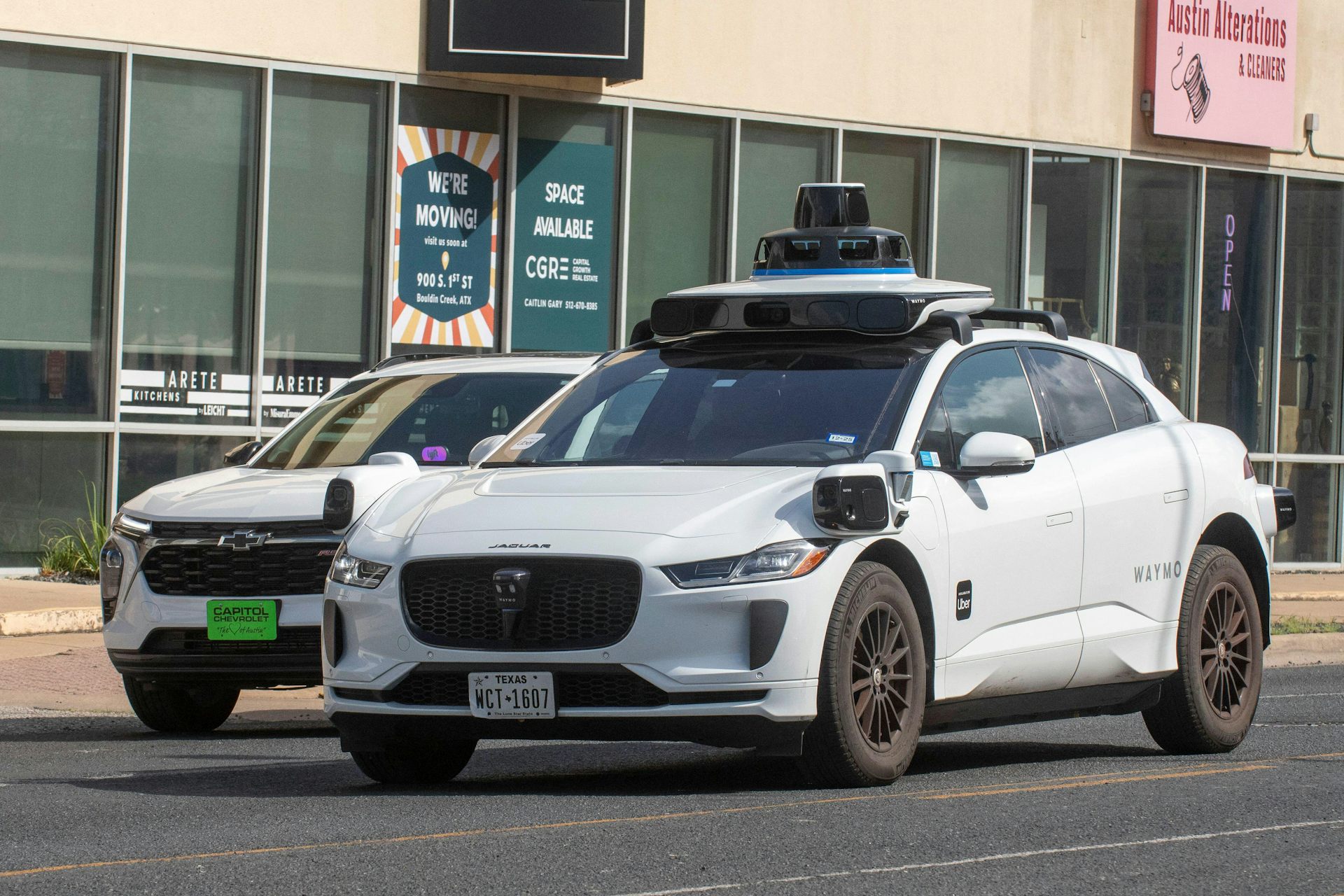Two Waymo taxis in a Texas street.