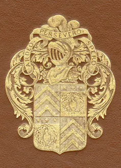 Une couverture de manuscrit brune ornée d’un blason doré représentant un casque et un bouclier de chevalier