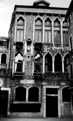 Une photo en noir et blanc d’une ancienne demeure de trois étages aux fenêtres étroites et hautes
