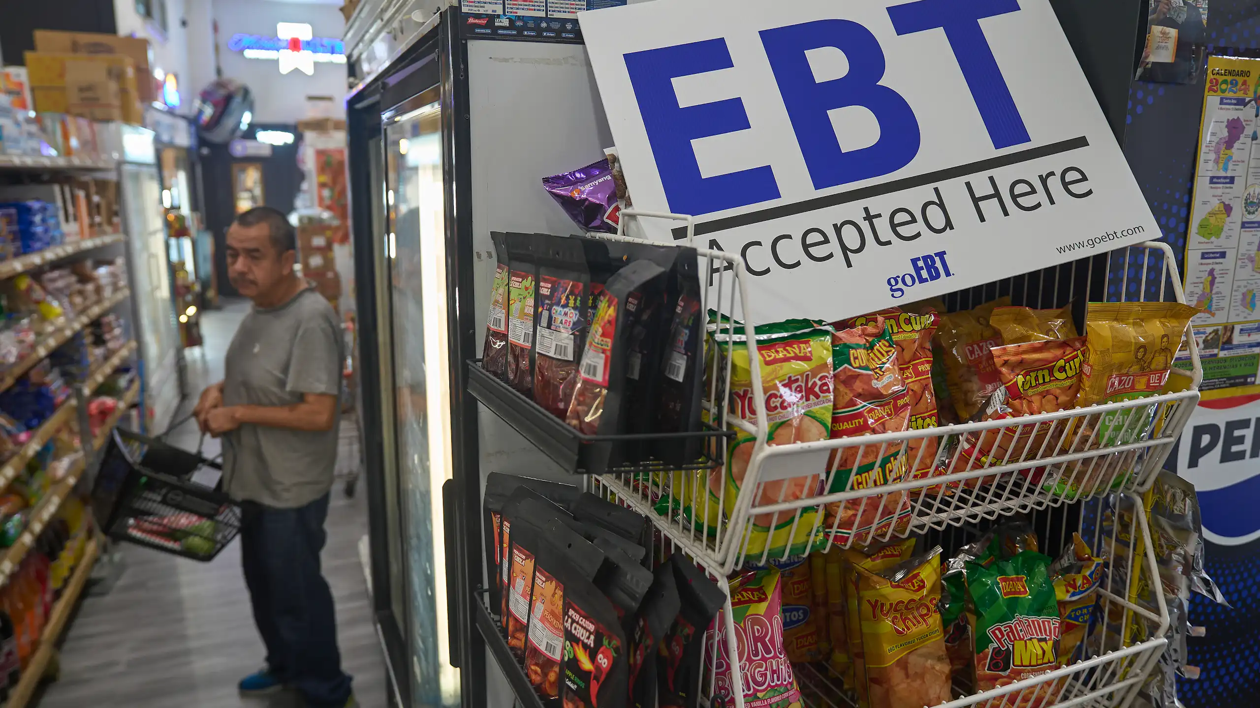 A man shops in a crowded store, with an EBT sign in the foreground.