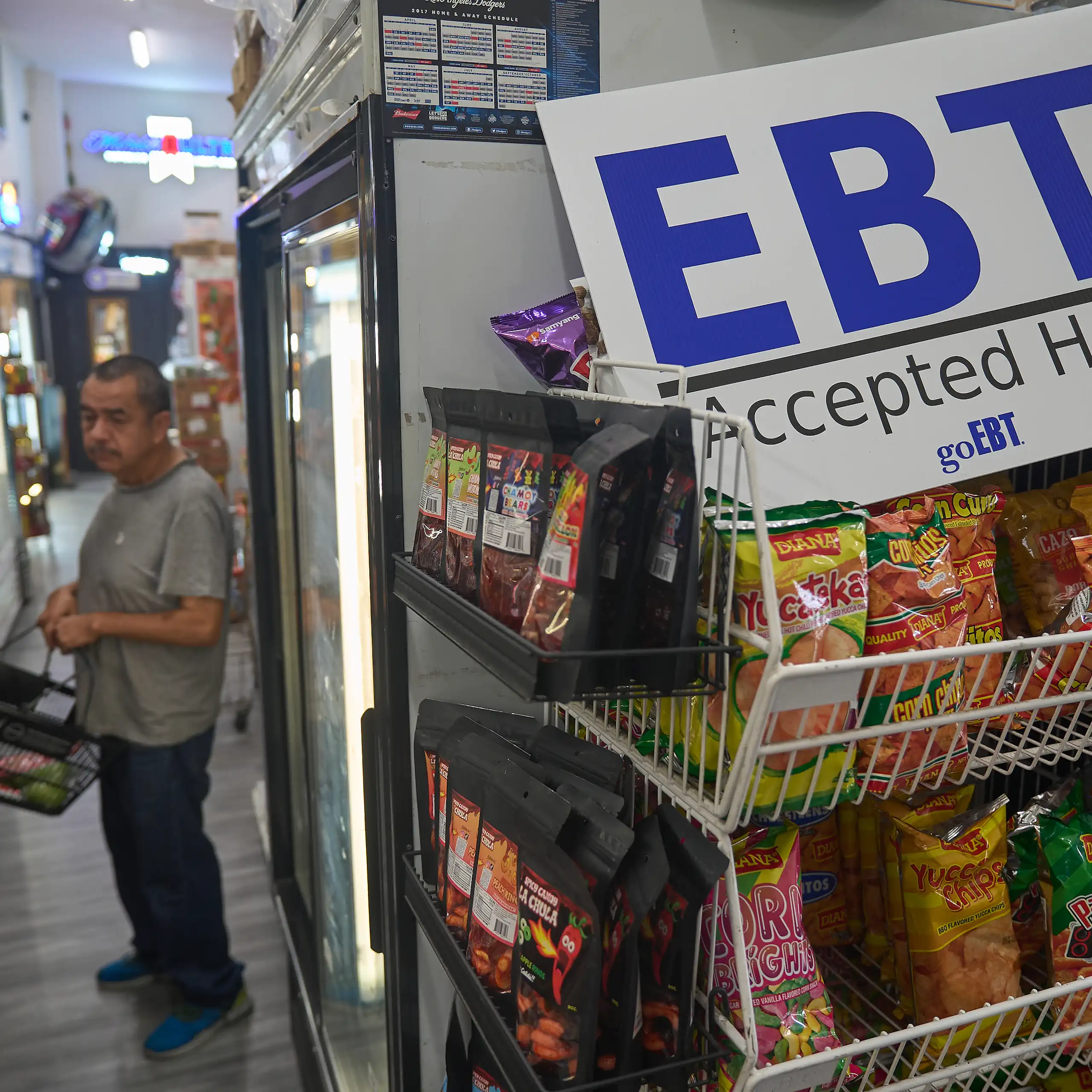 A man shops in a crowded store, with an EBT sign in the foreground.
