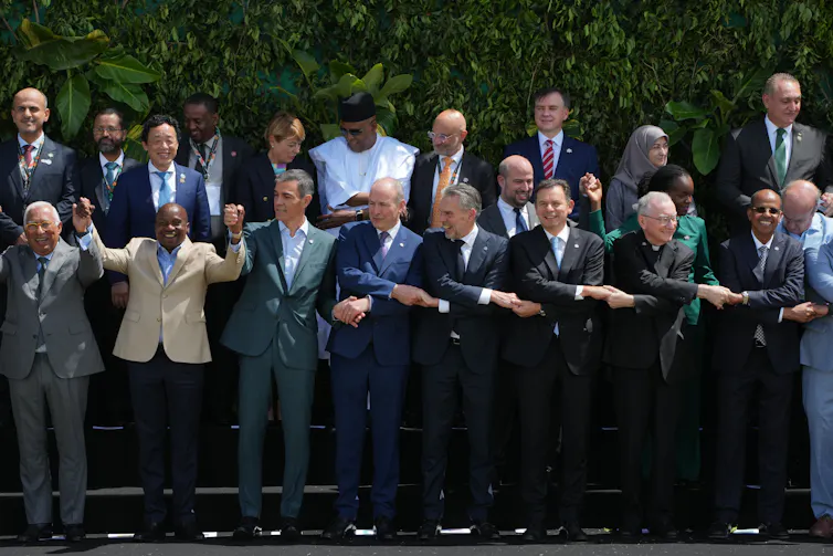 Global leaders attending the U.N. Climate Summit pose for a group photo and hold hands.