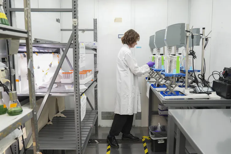 A scientist in a white coat works in a lab.