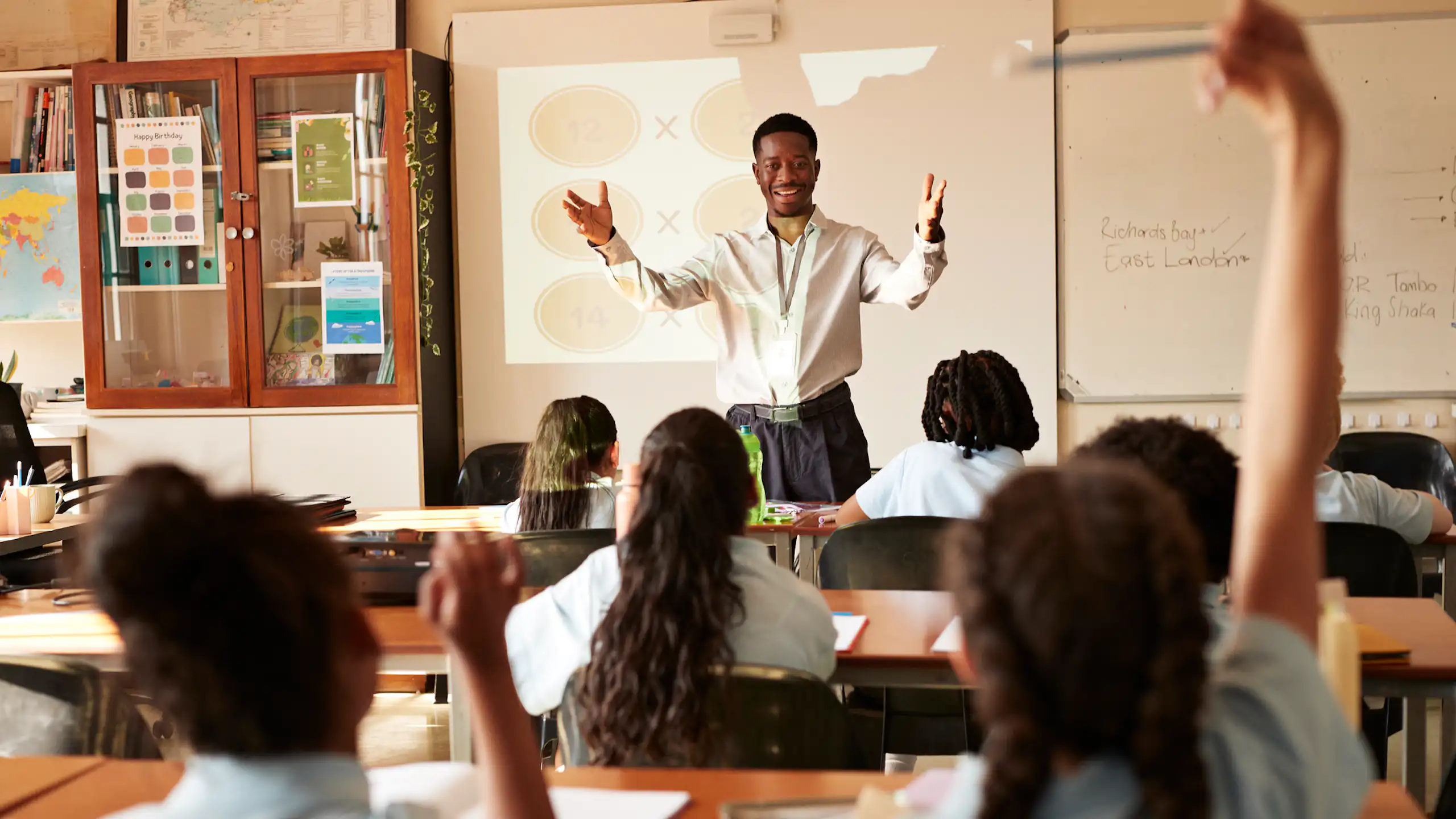 Man standing in front of children who are seated at desks