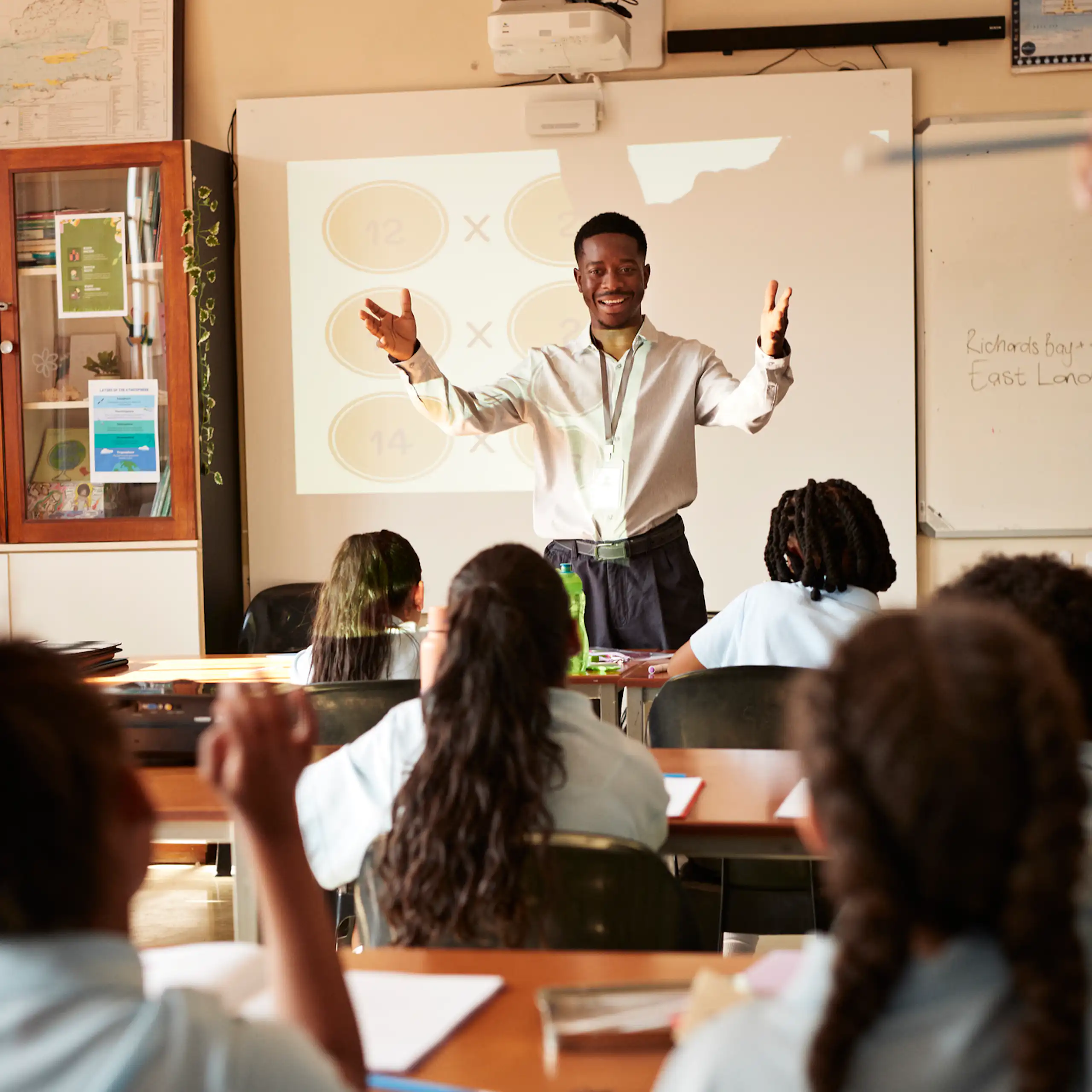 Man standing in front of children who are seated at desks