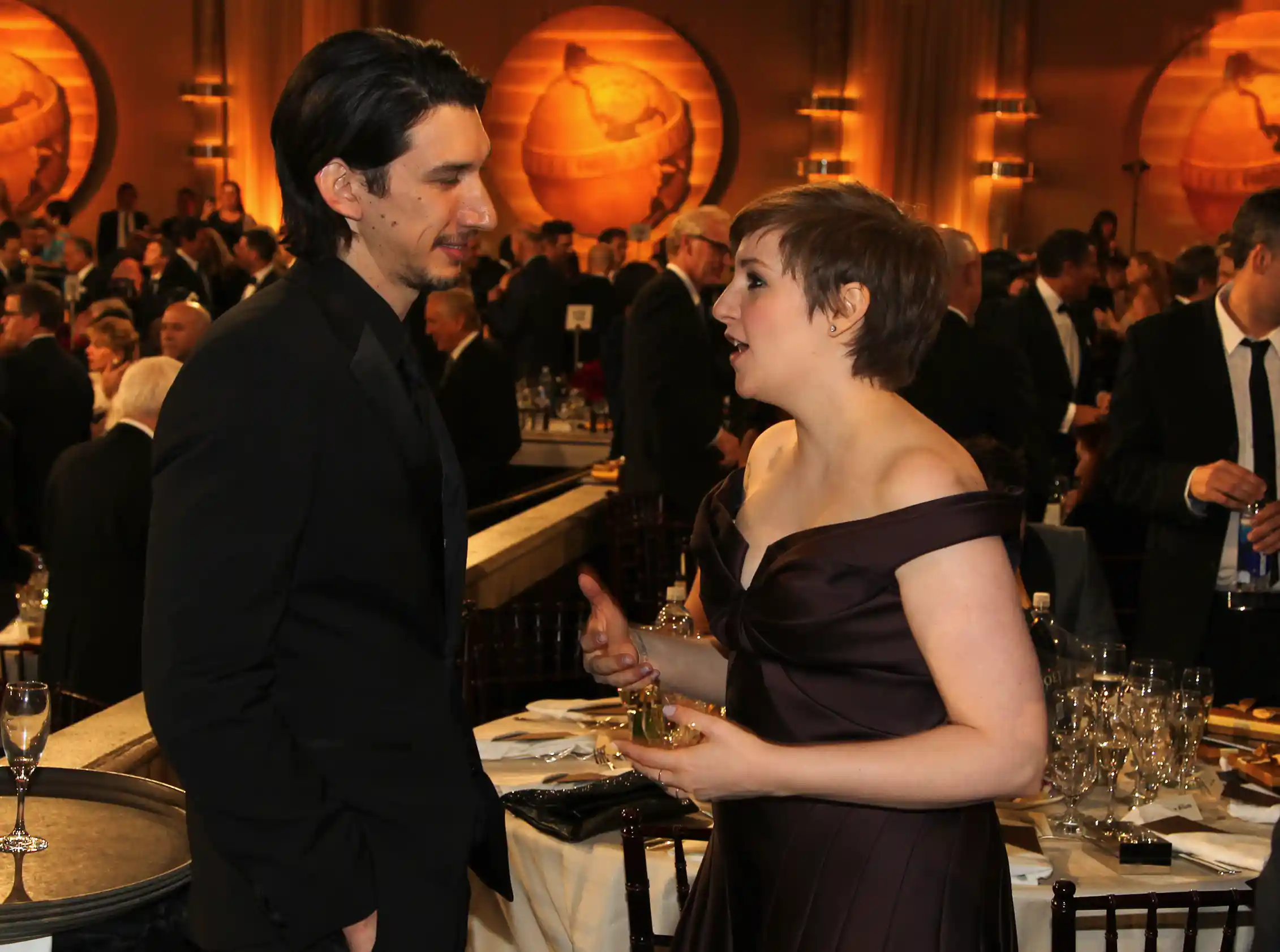 a woman in a black evening dress with a tall man in black suit, at a party