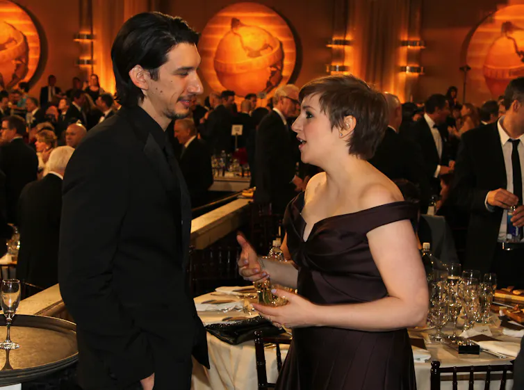 a woman in a black evening dress with a tall man in black suit, at a party