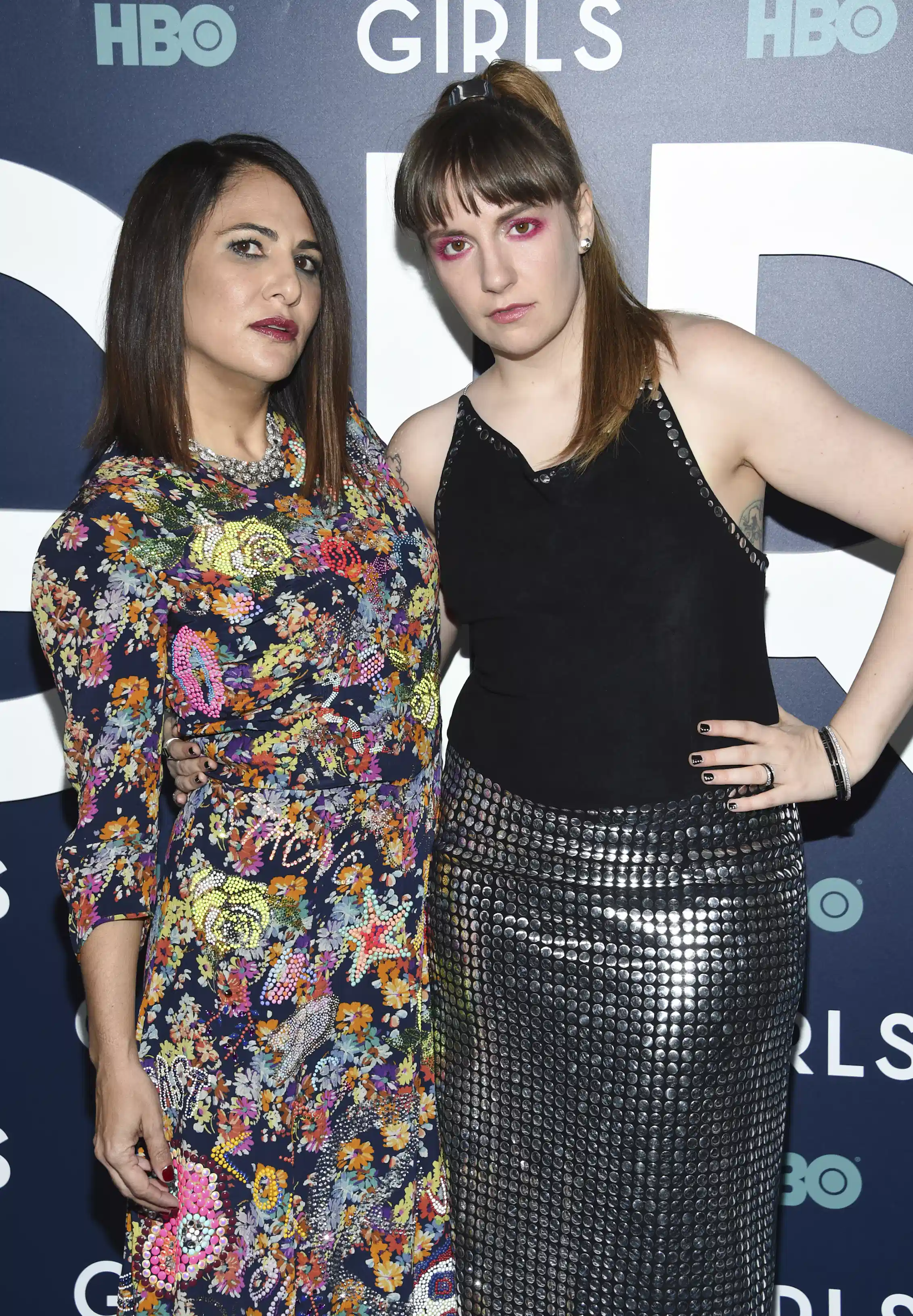 a woman in a floral dress with a woman in a slinky silver skirt and black top