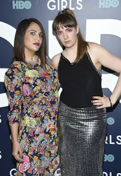 a woman in a floral dress with a woman in a slinky silver skirt and black top