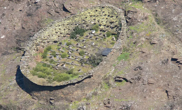 Un muro de piedra ovalado que alberga en su interior colmenas de piedra