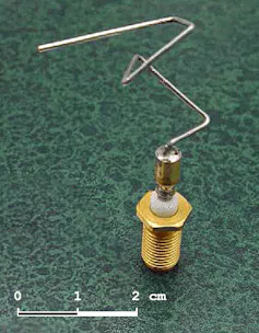 A small metal base supports a metal wire that has many complicated bends in it.