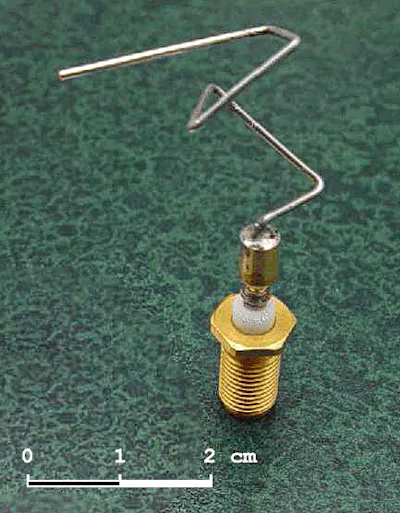 A small metal base supports a metal wire that has many complicated bends in it.