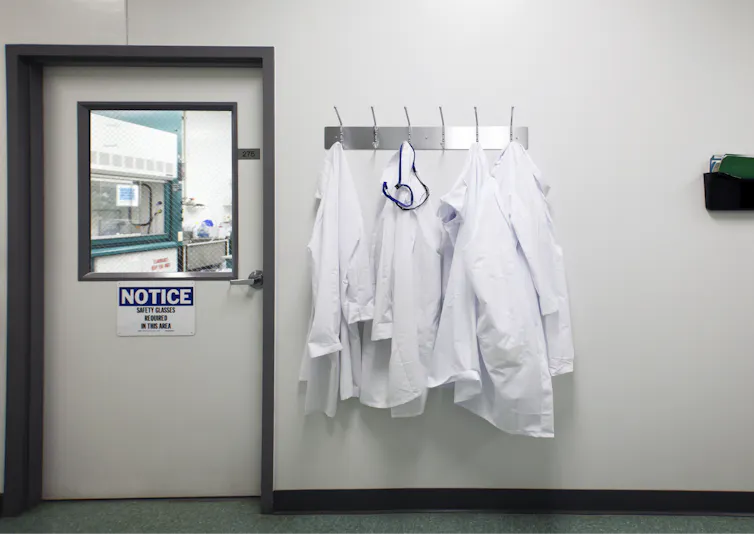 Lab coats on hooks outside a closed door to a lab