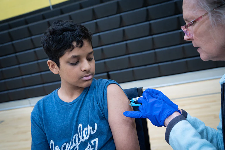 Un enfant en t-shirt bleu reçoit une injection de vaccin.