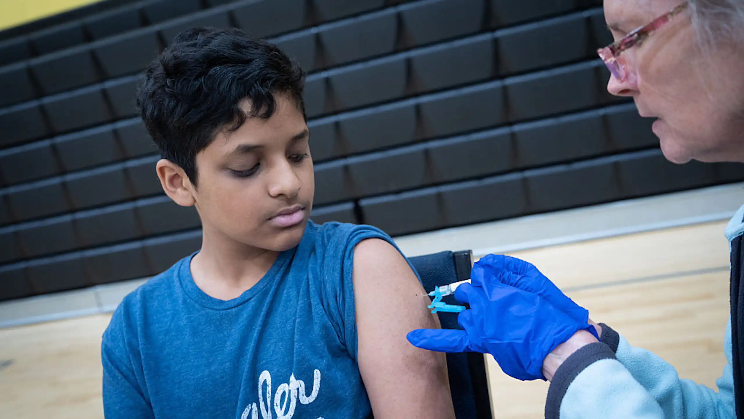 Un enfant en t-shirt bleu reçoit une injection de vaccin.