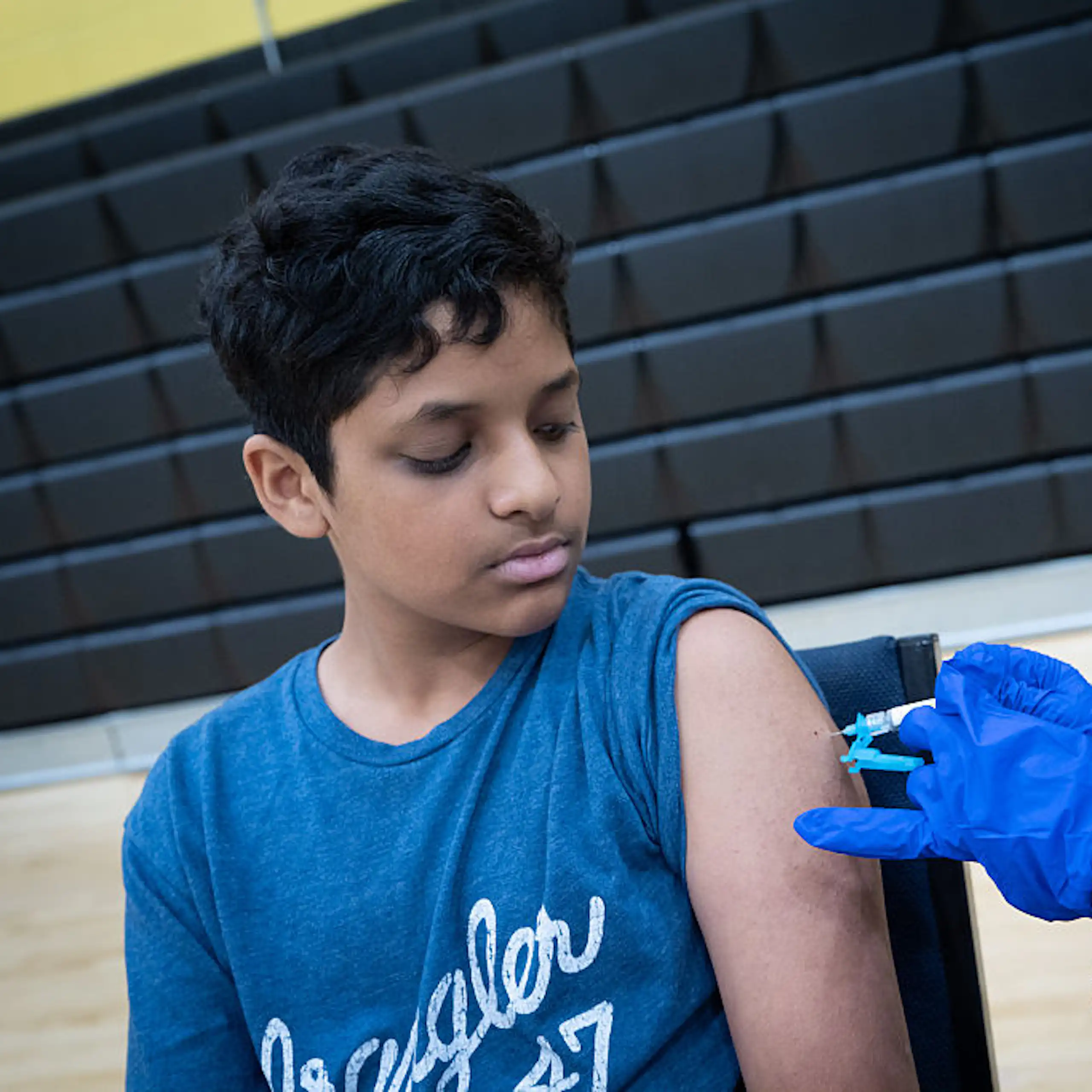 Un enfant en t-shirt bleu reçoit une injection de vaccin.