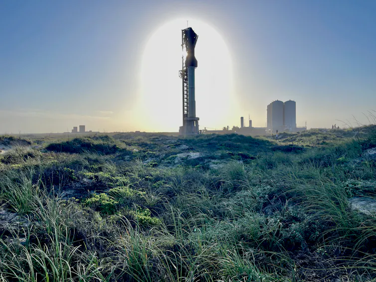 A large rocket sits on a launch pad in the midst of a wetland