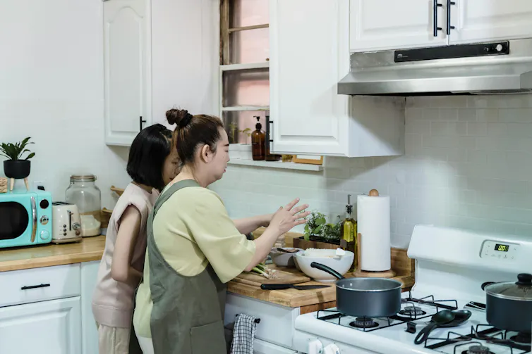 Asian mother and daughter preparing a meal in a modern home kitchen.