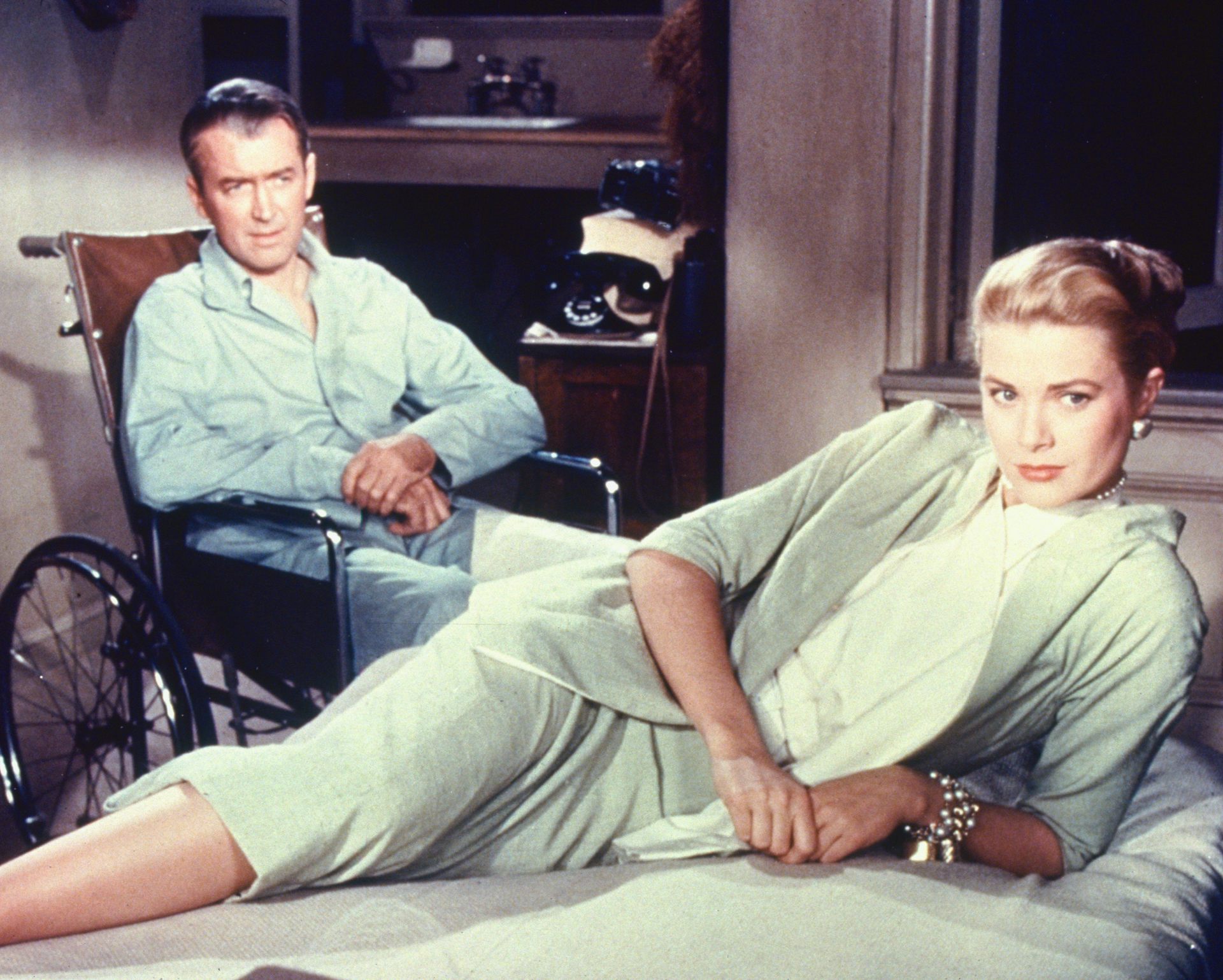 a man in a wheelchair behind a woman sprawled on a bed, looking away from him