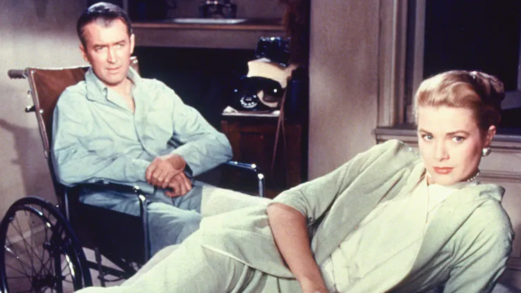 a man in a wheelchair behind a woman sprawled on a bed, looking away from him